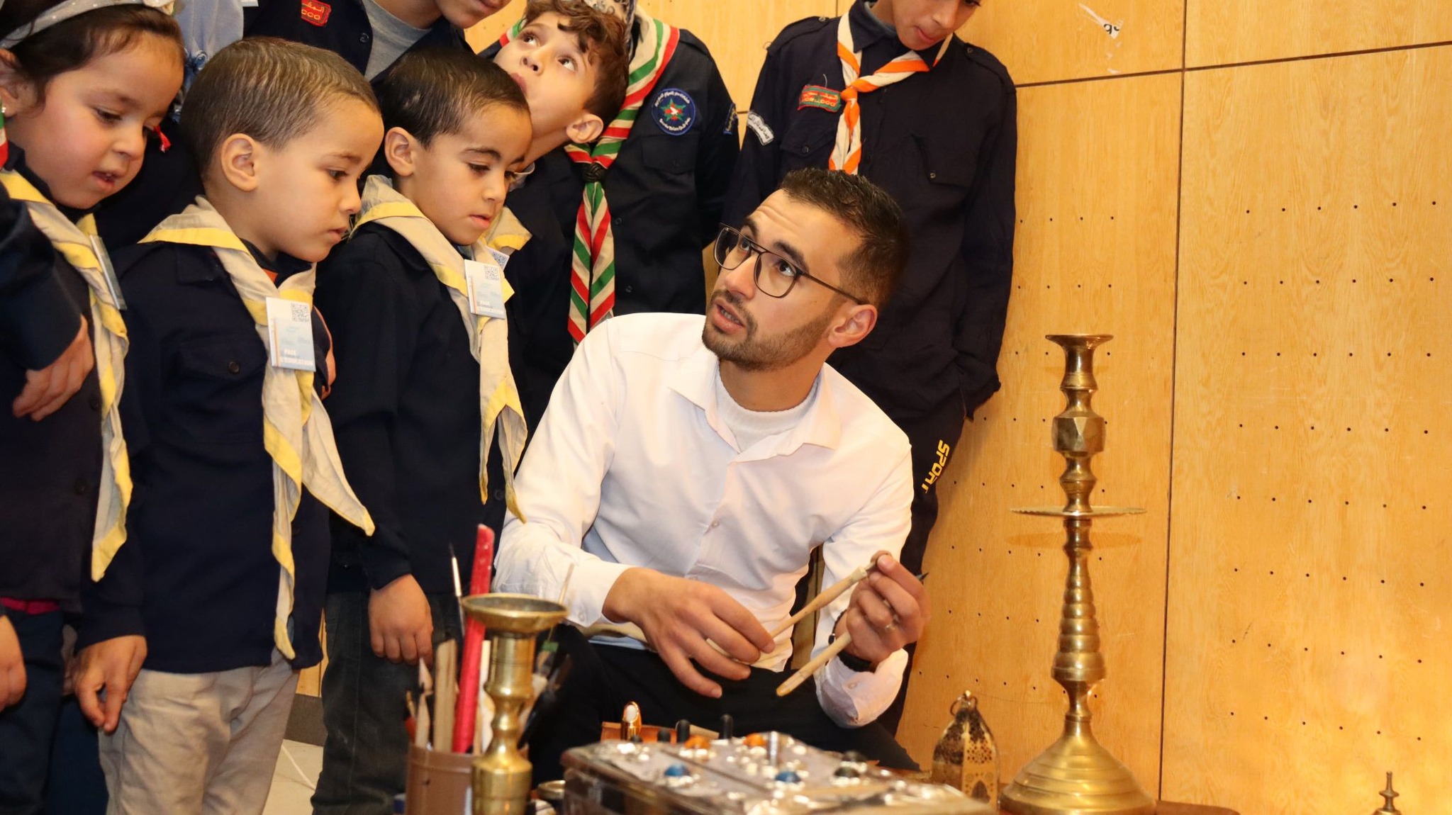 A scout leader guiding children during a hands-on learning workshop.